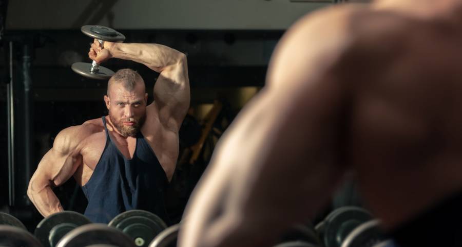 homem segurando halteres representando o que é um bodybuilding